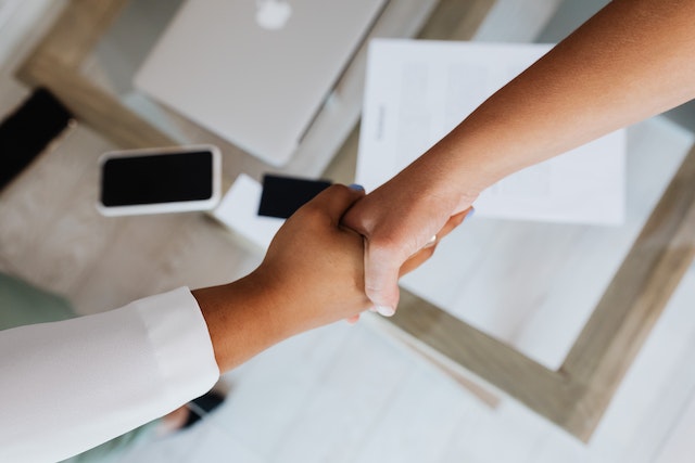 Picture of 2 people shaking hands over the top of a desk