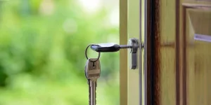 Picture of key sticking out of a lock on a wooden door.