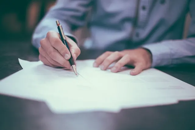 Picture of a person writing on a piece of paper with a pen